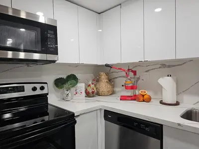 a kitchen with white cabinets and a microwave at The Ruby - Hot Tub - King beds - Close to LMC in Fort Lauderdale