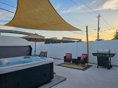 a hot tub on a patio with chairs and an umbrella at The Ruby - Hot Tub - King beds - Close to LMC in Fort Lauderdale