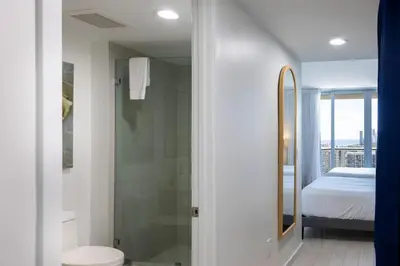a bathroom with a shower and a toilet and a bed at Family Beachwalk Studio- 29th floor in Hallandale Beach
