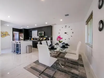 a dining room with a table and chairs and a clock at Luxury,3Bed 2Bath ,Pool,Grill,Parking in Hollywod in Hollywood
