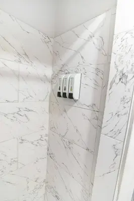a bathroom with white marble walls and white fixtures at Cozy Modern Studio Near Sunny Isles & Bal Harbour in North Miami