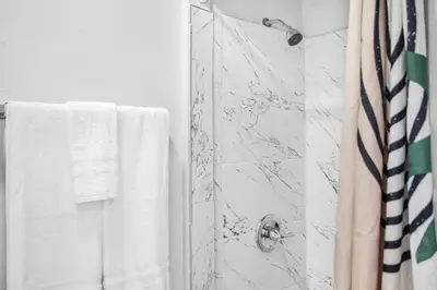 a bathroom with a shower with white towels at Cozy Modern Studio Near Sunny Isles & Bal Harbour in North Miami