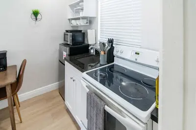 a small kitchen with a stove and a microwave at Modern Studio Apt • Prime North Miami Location in North Miami