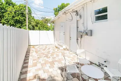 a patio with two chairs and a white fence at Spacious North Miami Studio | 2 Queen Beds in North Miami
