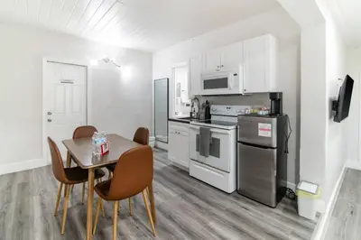 a kitchen with a table and a kitchen with white appliances at Spacious North Miami Studio | 2 Queen Beds in North Miami