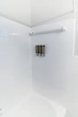 a white tiled bathroom with a towel rack at Spacious 1BR in North Miami | Near Beach & Dining in North Miami
