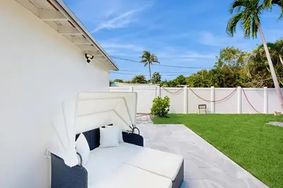 a white patio with a white fence and grass at Palm & Pool Retreat in Fort Lauderdale