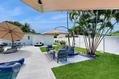 a patio with chairs and umbrellas next to a pool at Palm & Pool Retreat in Fort Lauderdale