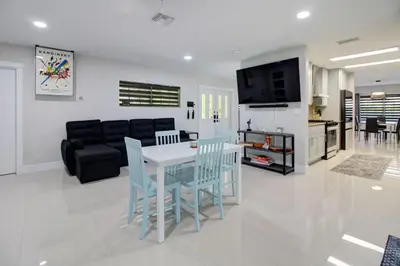 a kitchen and a living room with a table and chairs at Vista Azul Lake Front Home with Hot Tub and Swim Spa, Fishing Dock, Gym, Game Room with Darts, Ping Pong, A Pool Table and more! in Miami Lakes
