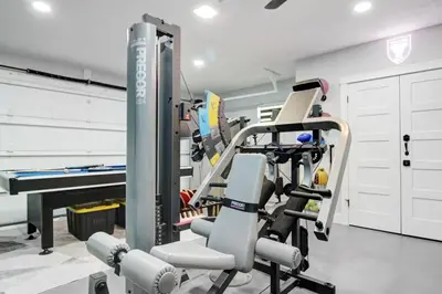 a room with a gym with a treadmill at Vista Azul Lake Front Home with Hot Tub and Swim Spa, Fishing Dock, Gym, Game Room with Darts, Ping Pong, A Pool Table and more! in Miami Lakes