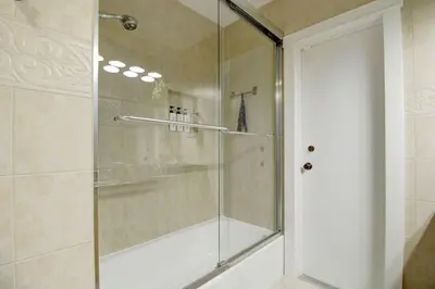 a shower with a glass door in a bathroom at Vista Azul Lake Front Home with Hot Tub and Swim Spa, Fishing Dock, Gym, Game Room with Darts, Ping Pong, A Pool Table and more! in Miami Lakes