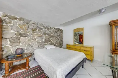 a bedroom with a bed and a stone wall at 5 Mi to Hollywood Blvd! Miramar Apt with Shared Pool in Miramar