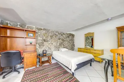 a bedroom with a bed and a stone wall at 5 Mi to Hollywood Blvd! Miramar Apt with Shared Pool in Miramar
