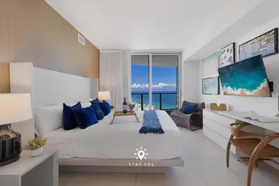 a bedroom with a large bed with blue pillows and a desk at Beautiful 1BR Apartment with Ocean View Balcony in Hollywood