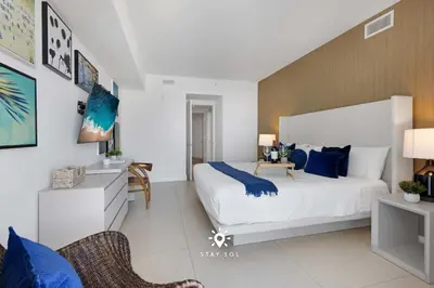 a bedroom with a large white bed with blue pillows at Beautiful 1BR Apartment with Ocean View Balcony in Hollywood