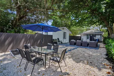 a table and chairs with an umbrella in a backyard at Miami Heart Retreat, Stylish & Central With Games in Miami
