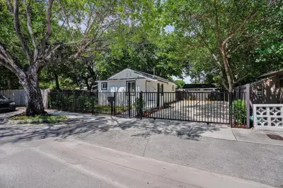 a fence in front of a house with a tree at Miami Heart Retreat, Stylish & Central With Games in Miami