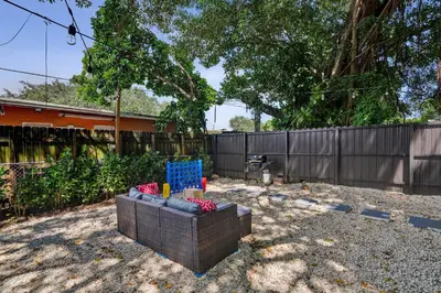 a wicker chair sitting in a yard next to a fence at Heart of Miami Oasis, Modern, Steps from It All in Miami