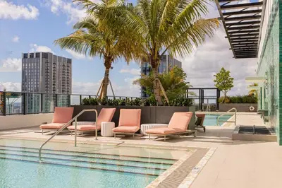 a pool with chairs and palm trees on a building at The Crosby Miami World Center in Miami