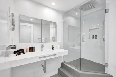 a white bathroom with a shower and a sink at Oceanfront Luxury 3BR 3BA Condo with Resort Pools Gym and Sauna 902 in Miami Beach