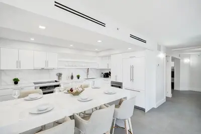 a white kitchen with a large white table and chairs at Oceanfront Luxury 3BR 3BA Condo with Resort Pools Gym and Sauna 902 in Miami Beach