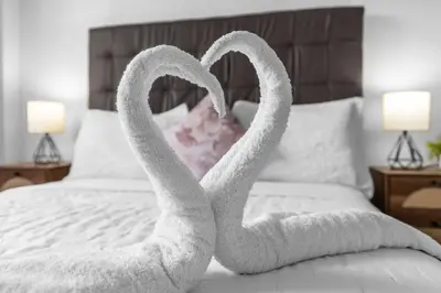 two towels shaped like swans sitting on a bed at Urban Escape 2 Bed Unit In Miami near Whole Foods in North Miami
