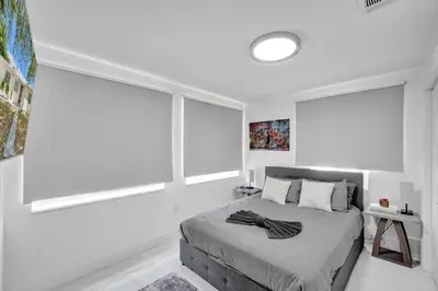 a white bedroom with a bed and two large windows at Charming 3 bedroom getaway house in Hollywood in Hollywood