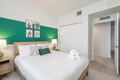 a bedroom with a white bed with a green accent wall at Event-Ready 2BR 2BA Near Stadium & Beach includes Parking and Washer and Dryer in Hallandale Beach