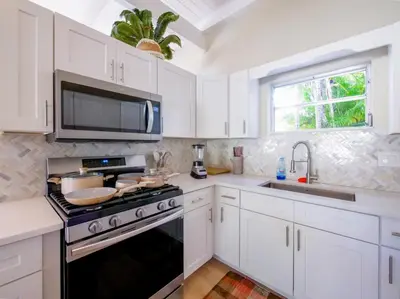 a kitchen with white cabinets and a stove and a sink at 3BD Tropical Luxe Stay with Pool, Gameroom and Grill in Fort Lauderdale
