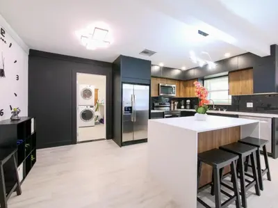 a kitchen with a white island and black walls at Dania Beach 3-bedroom house - Pool,Parking,Grill in Dania Beach