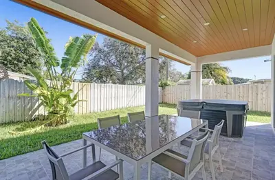 a patio with a table and chairs and a grill at New Construction Villa HotTub Heated Pool Gameroom in Fort Lauderdale