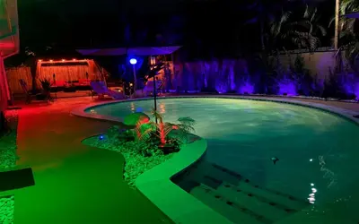 a swimming pool at night with purple lights at Garden of Manors - Men Only Clothing Optional Boutique Guesthouse in Florida in Fort Lauderdale