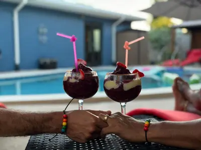 two people are holding up two glasses with desserts at Garden of Manors - Men Only Clothing Optional Boutique Guesthouse in Florida in Fort Lauderdale