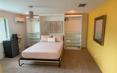a bedroom with a bed with pink pillows at Garden of Manors - Men Only Clothing Optional Boutique Guesthouse in Florida in Fort Lauderdale
