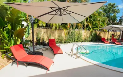 an umbrella and chairs next to a swimming pool at Garden of Manors - Men Only Clothing Optional Boutique Guesthouse in Florida in Fort Lauderdale