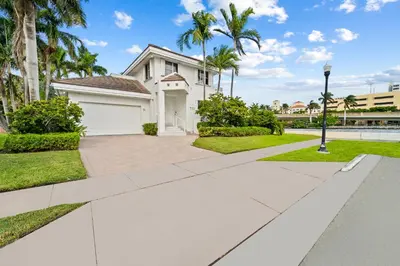 a white house with palm trees and a sidewalk at Villa Harrison . in Hollywood