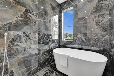a bathroom with a white tub and a window at Upscale 4 BDRM Retreat - Mins to Las Olas & Beach in Fort Lauderdale