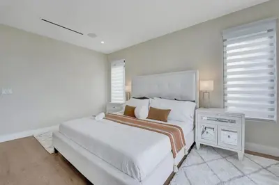 a white bedroom with a large bed and a window at Upscale 4 BDRM Retreat - Mins to Las Olas & Beach in Fort Lauderdale