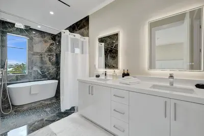 a white bathroom with a tub and a sink and a bath tub at Upscale 4 BDRM Retreat - Mins to Las Olas & Beach in Fort Lauderdale