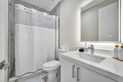 a white bathroom with a toilet and a sink at Upscale 4 BDRM Retreat - Mins to Las Olas & Beach in Fort Lauderdale