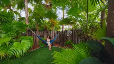 a woman swinging on a hammock in a garden at Villa Calma Hidden Tropical Gem with Gym and Pool in Hollywood