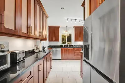 a kitchen with wooden cabinets and a stainless steel refrigerator at Villa Calma Hidden Tropical Gem with Gym and Pool in Hollywood