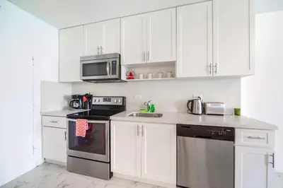 a kitchen with white cabinets and a stove and a microwave at Ocean Breeze Retreat in Miami Beach in Miami Beach