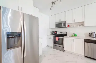 a kitchen with white cabinets and a stainless steel refrigerator at Ocean Breeze Retreat in Miami Beach in Miami Beach