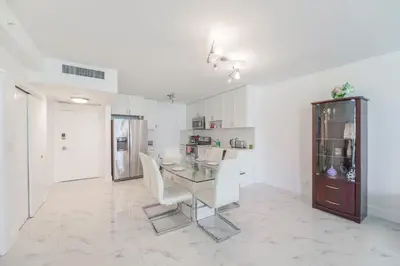 a dining room with a glass table and white chairs at Ocean Breeze Retreat in Miami Beach in Miami Beach