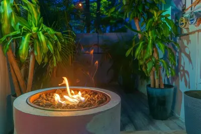 a fire pit with a candle in it next to plants at Steps from Airport Hot Tub Bbq Boat Slip in Dania Beach