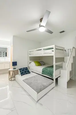 a white bedroom with a bunk bed and a ceiling at Waterfront HotTub Steps from the Airport Boat Slip in Dania Beach