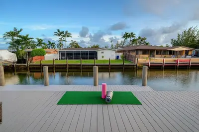 a green mat with a toy on it next to the water at Waterfront HotTub Steps from the Airport Boat Slip in Dania Beach