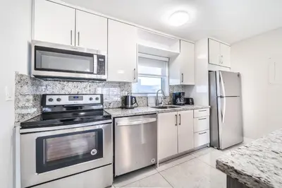 a kitchen with stainless steel appliances and white cabinets at Cozy place near Beachside in Sunny Isles Beach