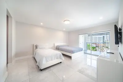 a white bedroom with a bed and a window at Cozy place near Beachside in Sunny Isles Beach